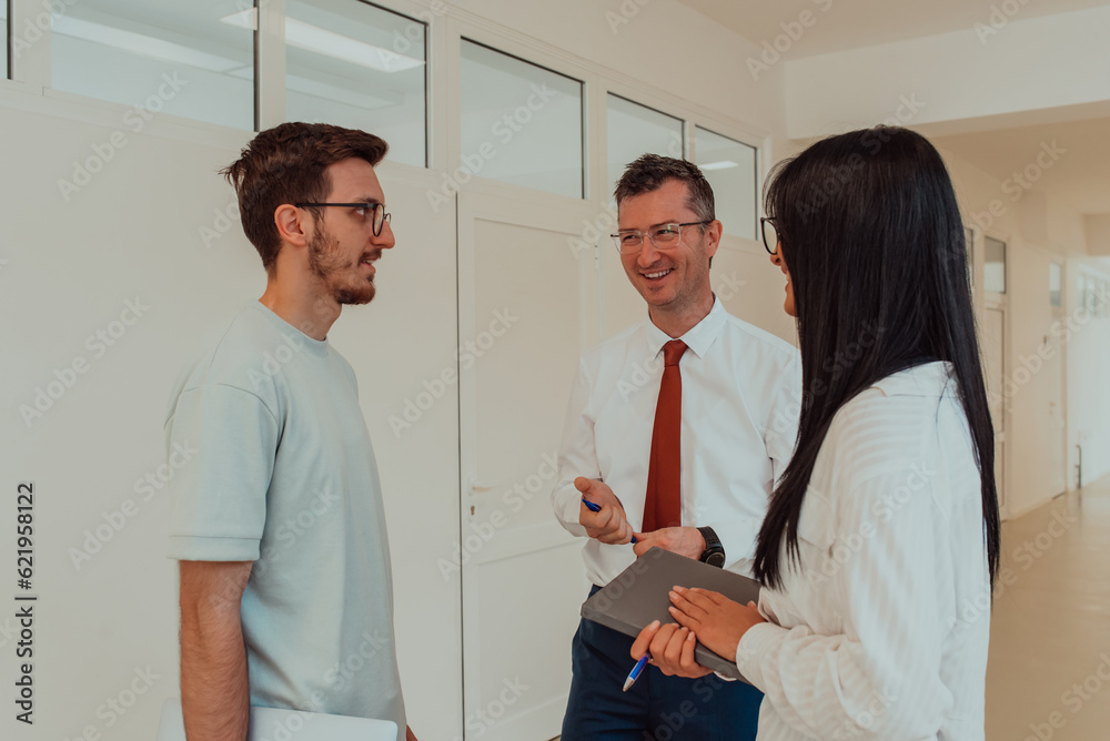 Obraz premium The director conducts a conversation with the secretary and a young programmer in a modern and spacious corridor of a large company, discussing various business topics and projects.