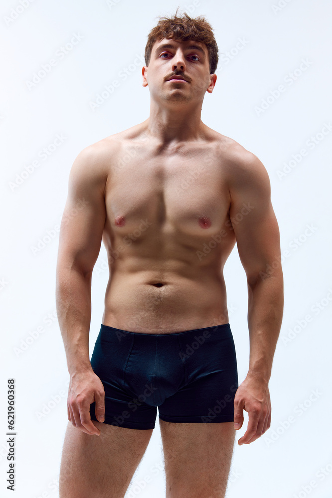 Portrait of handsome young man with mustache, posing shirtless in underwear against grey studio background. Muscular, sportive body. Nan's beauty, sportive and healthy lifestyle, athletic body concept Portrait of handsome young man with mustache, posing shirtless in underwear against grey studio background. Muscular, sportive body. Nan's beauty, sportive and healthy lifestyle, athletic body concept