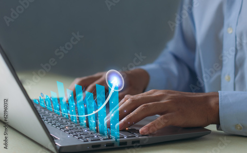 Business finance technology and investment concept, businessman and graph development to success and growing, analyzing financial graph on virtual screen with laptop on the table..