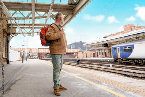 Traveler with a suitcase and  suit waiting for a train at the train station.   Travel concept. © Iryna