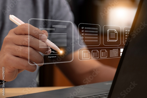 Electronic signature and paperless office concept. A businessman uses a pen to sign electronic documents on digital documents on a virtual screen. E-signing. Technology and document management