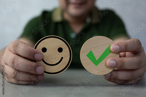Man hand holding check mark and happy happy face on circle wood block. Satisfaction in service. Rating very impressed. Customer service satisfaction survey concept