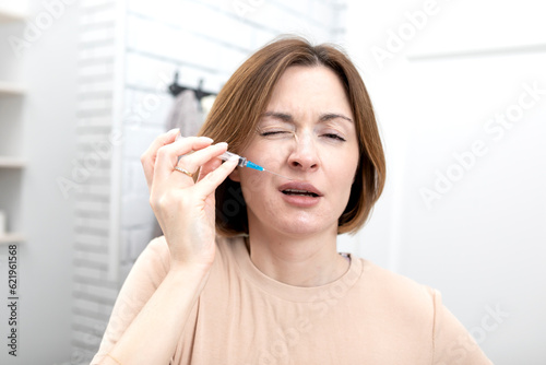 Attractive woman doing facial injections herself