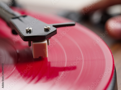 Close-up. Record player needle on red vinyl record. Advertising for a recording studio, music store, equipment.