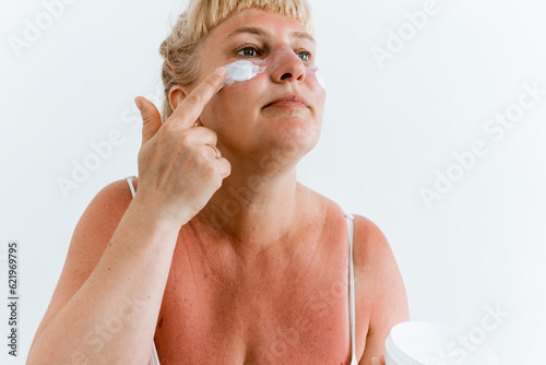 Fotografie Middle-aged woman applying after-sun cream