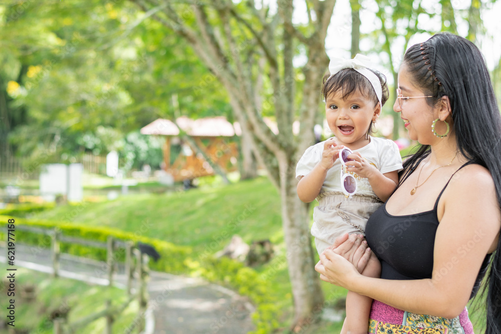 latina mother holding her smiling baby daughter and proudly admiring her innocence