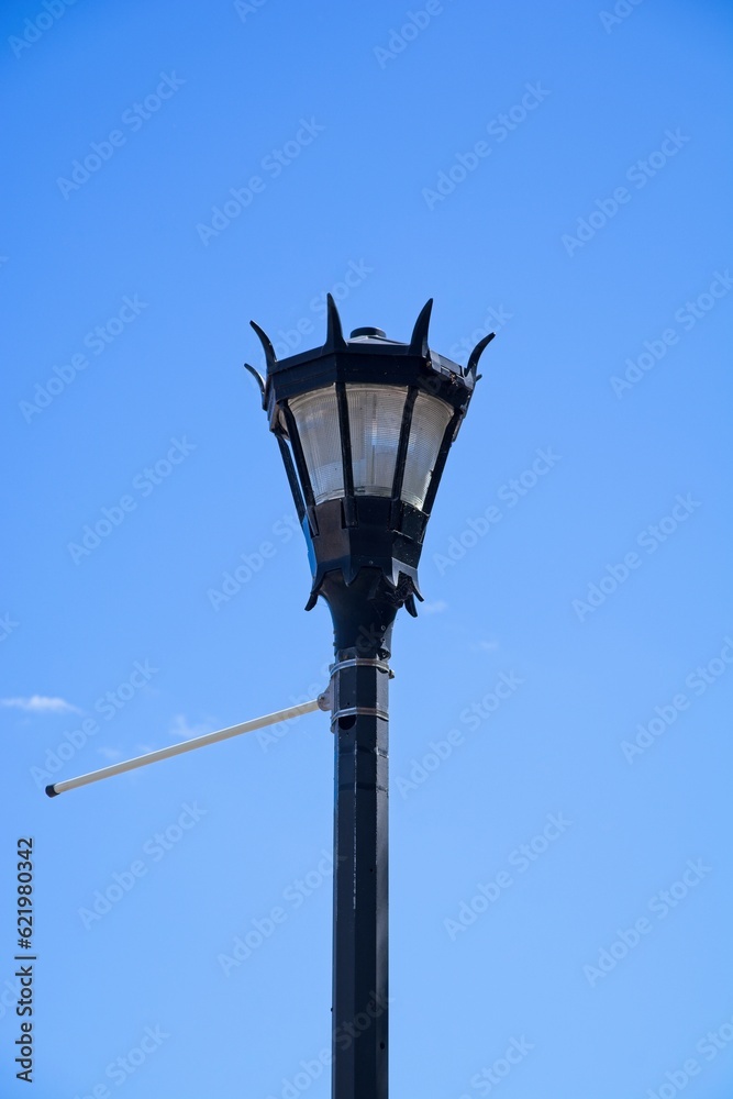 Black ornate street light set against bright blue sky