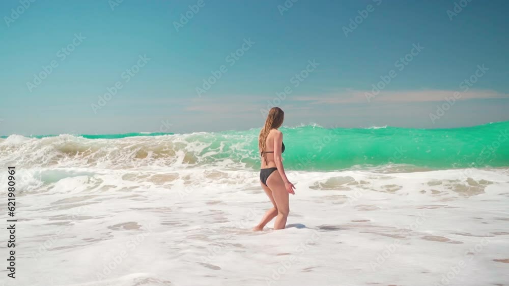 Attractive female tourist in black bikini standing in sea and waves covering her. Woman having fun in waves enjoying vacation on ocean. Summer vacation and travel Attractive female tourist in black bikini standing in sea and waves covering her. Woman having fun in waves enjoying vacation on ocean. Summer vacation and travel