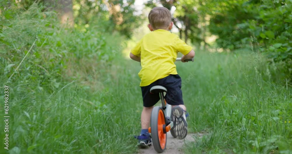 Child ride on bicycle through the forest on summertime vacations. Child ride on bicycle through the forest on summertime vacations.