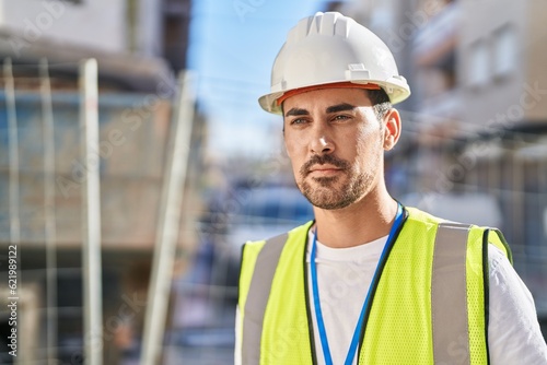 Young hispanic man architect standing with relaxed expression at street