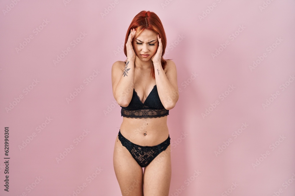 Obraz premium Young caucasian woman wearing lingerie over pink background with hand on head, headache because stress. suffering migraine.