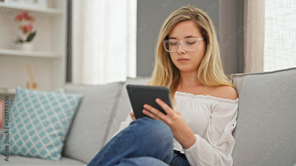 Young blonde woman wearing glasses using touchpad at home Young blonde woman wearing glasses using touchpad at home