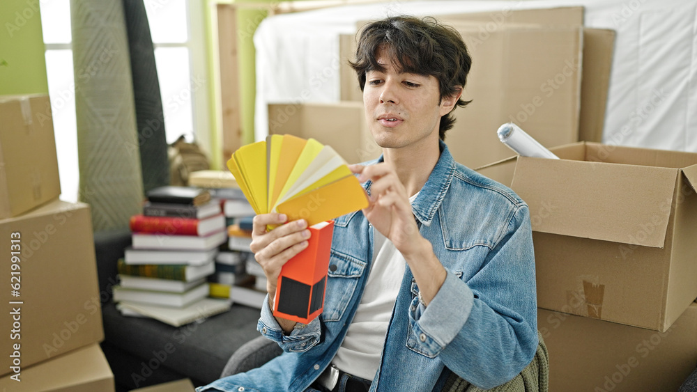Young hispanic man choosing paint color at new home Young hispanic man choosing paint color at new home
