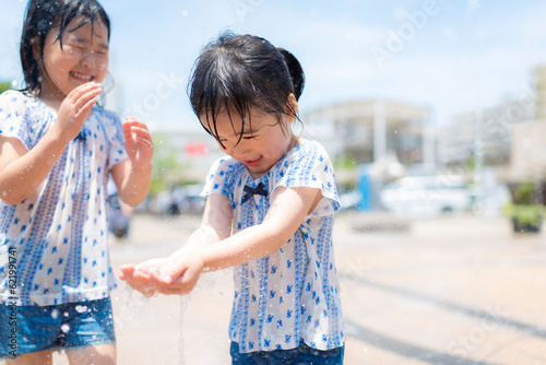 広場の噴水で水遊びしている女の子