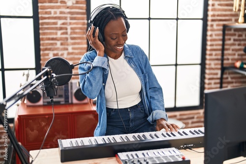 African american woman musician playing piano keyboard at music studio