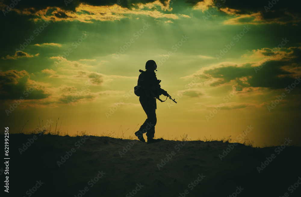 Silhouette of US soldier with rifle at sunset standing as the sun sets in the background Silhouette of US soldier with rifle at sunset standing as the sun sets in the background