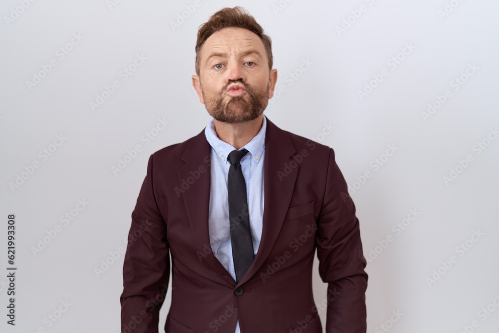 Middle age business man with beard wearing suit and tie looking at the camera blowing a kiss on air being lovely and sexy. love expression. Middle age business man with beard wearing suit and tie looking at the camera blowing a kiss on air being lovely and sexy. love expression.