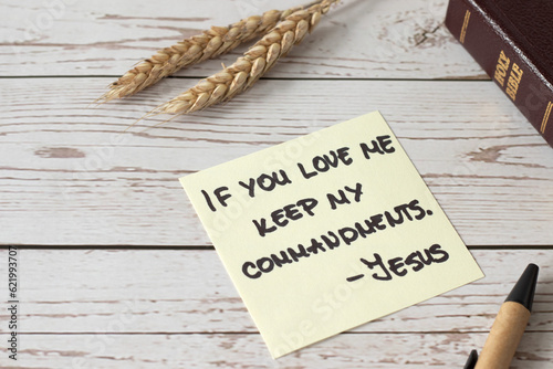 If you love Me, keep My commandments, Jesus Christ's words written in holy bible book with ripe wheat on wooden table. Close-up. Christian disciples obedience and faith in God, biblical concept. photo