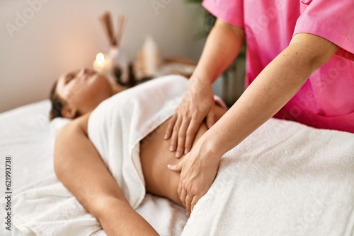 Young beautiful hispanic woman lying on table having massage at beauty salon