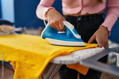 Young beautiful hispanic woman ironing clothes at laundry room