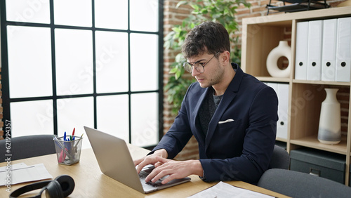 Young hispanic man business worker using laptop with serious face at office