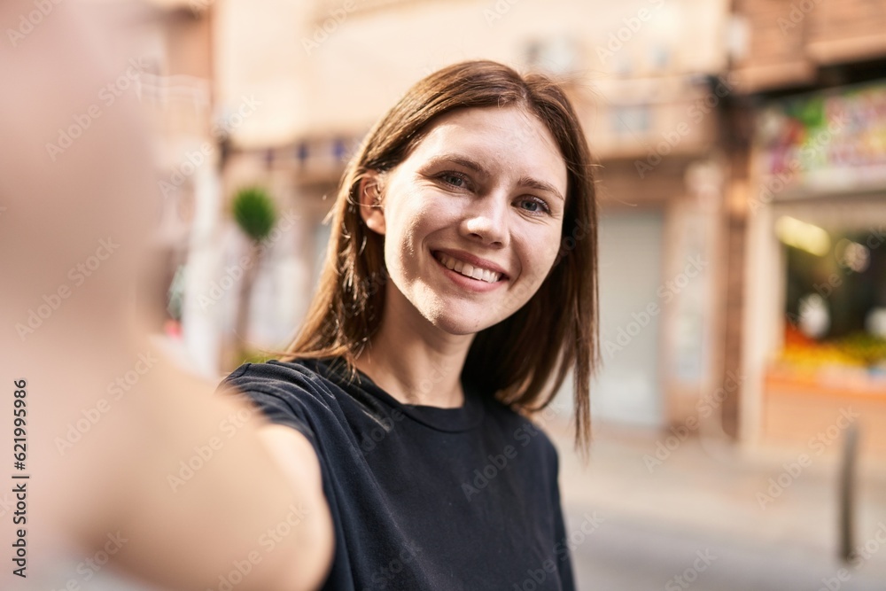 Young blonde woman smiling confident making selfie by the camera at street