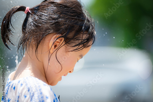 広場の噴水で水遊びしている3歳の女の子