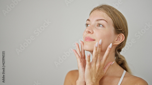 Young blonde woman touching face over isolated white background