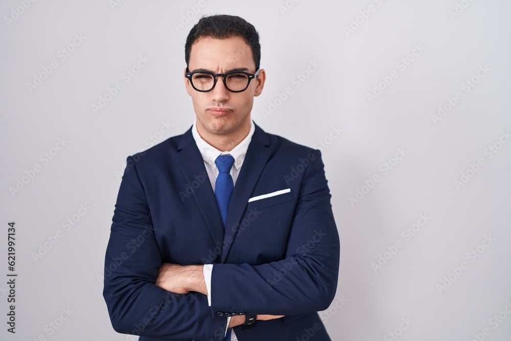 Young hispanic man wearing suit and tie skeptic and nervous, disapproving expression on face with crossed arms. negative person. Young hispanic man wearing suit and tie skeptic and nervous, disapproving expression on face with crossed arms. negative person.