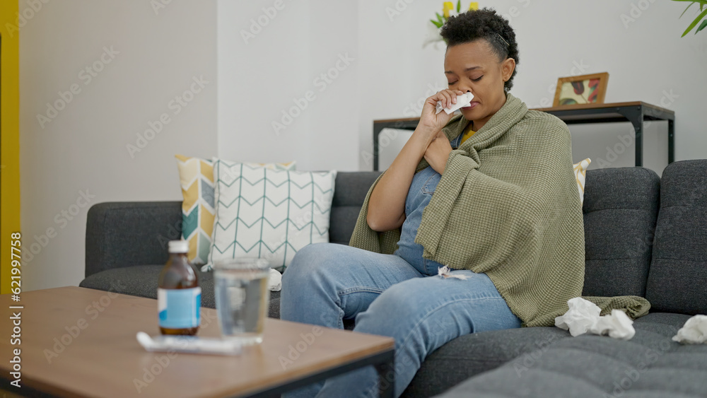 Young pregnant woman sitting on sofa being sick at home