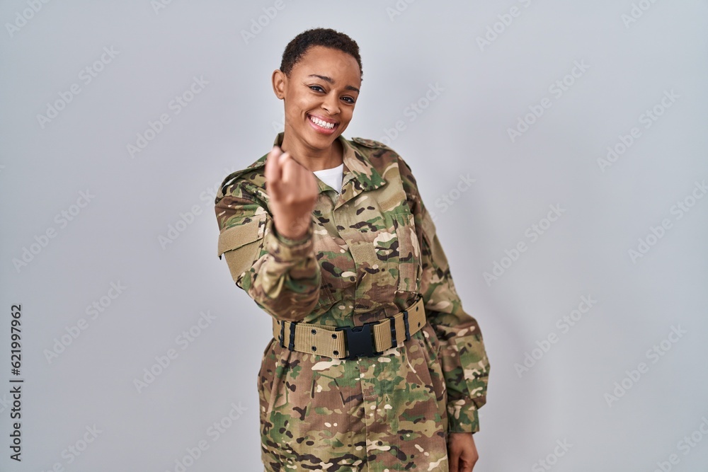 Beautiful african american woman wearing camouflage army uniform beckoning come here gesture with hand inviting welcoming happy and smiling
