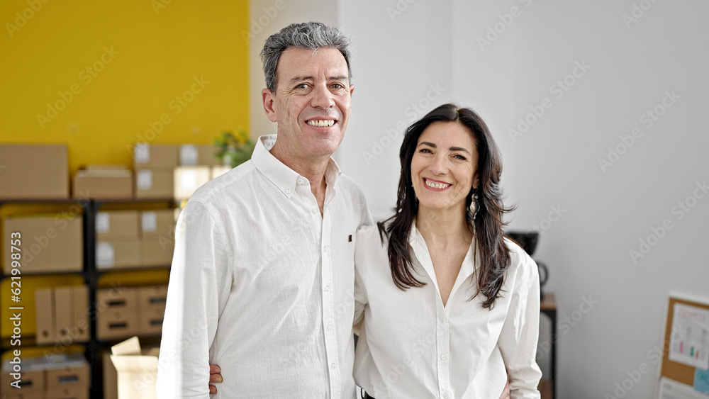 Senior man and woman ecommerce business workers hugging each other at office Senior man and woman ecommerce business workers hugging each other at office