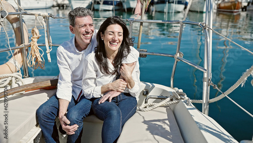 Senior man and woman couple hugging each other sitting together on boat at boat