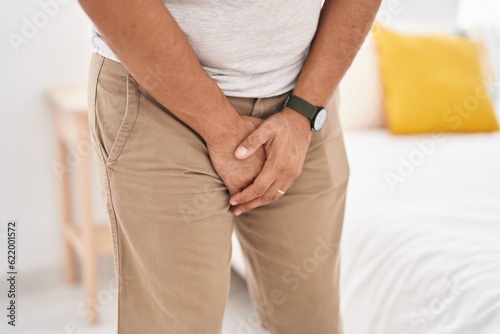 Young latin man covering his genitals with hands at bedroom photo