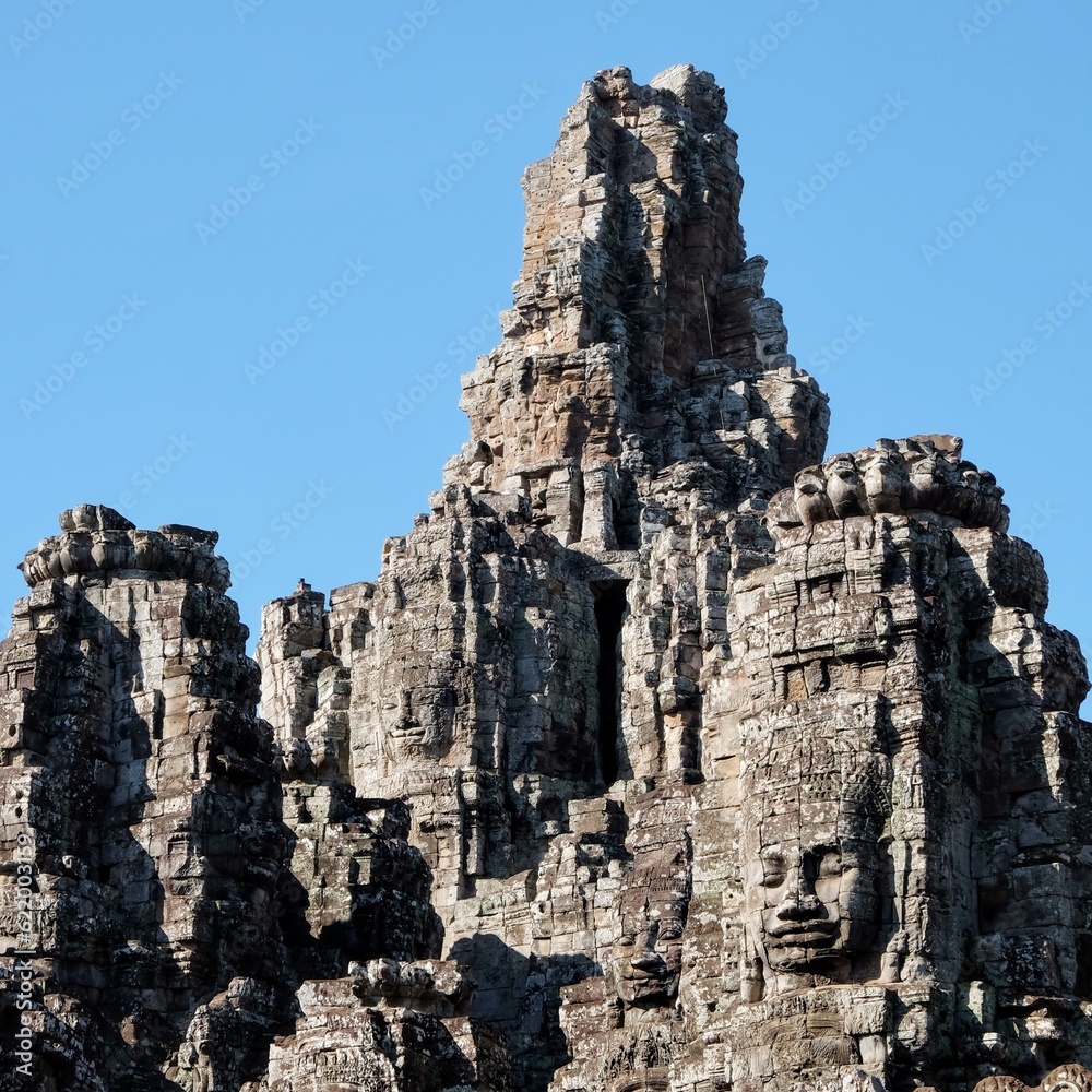 The majestic stone towers of the Bayon Temple in Cambodia, an iconic symbol of Khmer architecture, under a clear blue sky.