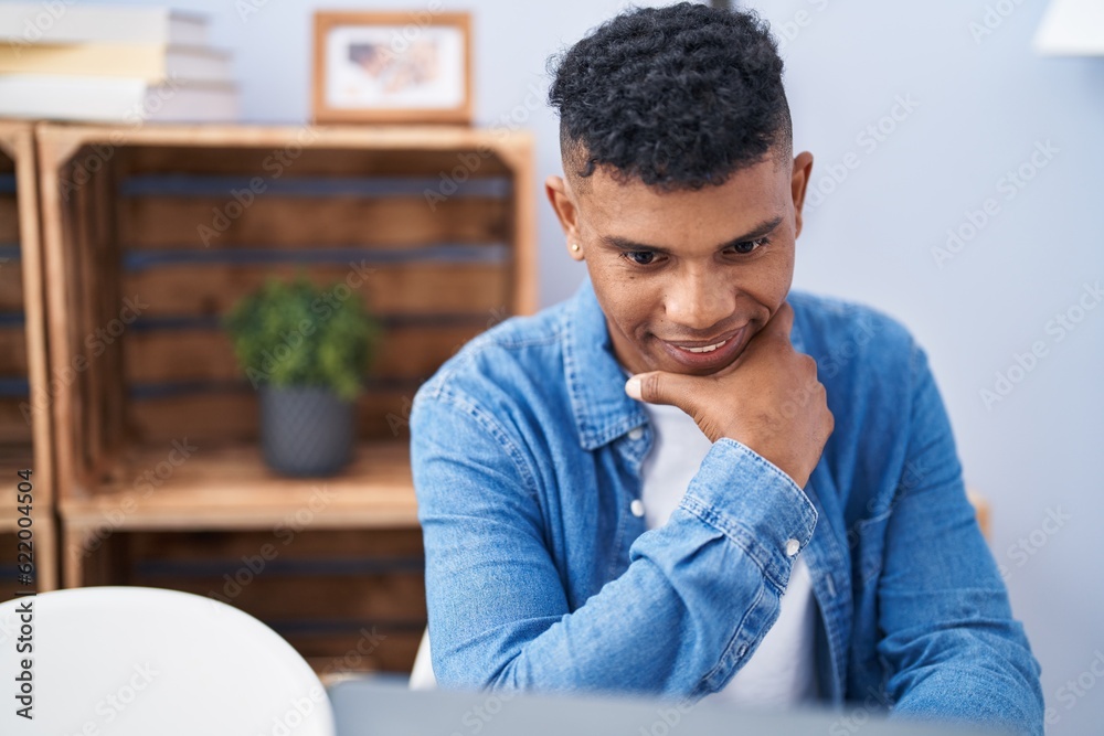 Young latin man smiling confident sitting on table at home Young latin man smiling confident sitting on table at home