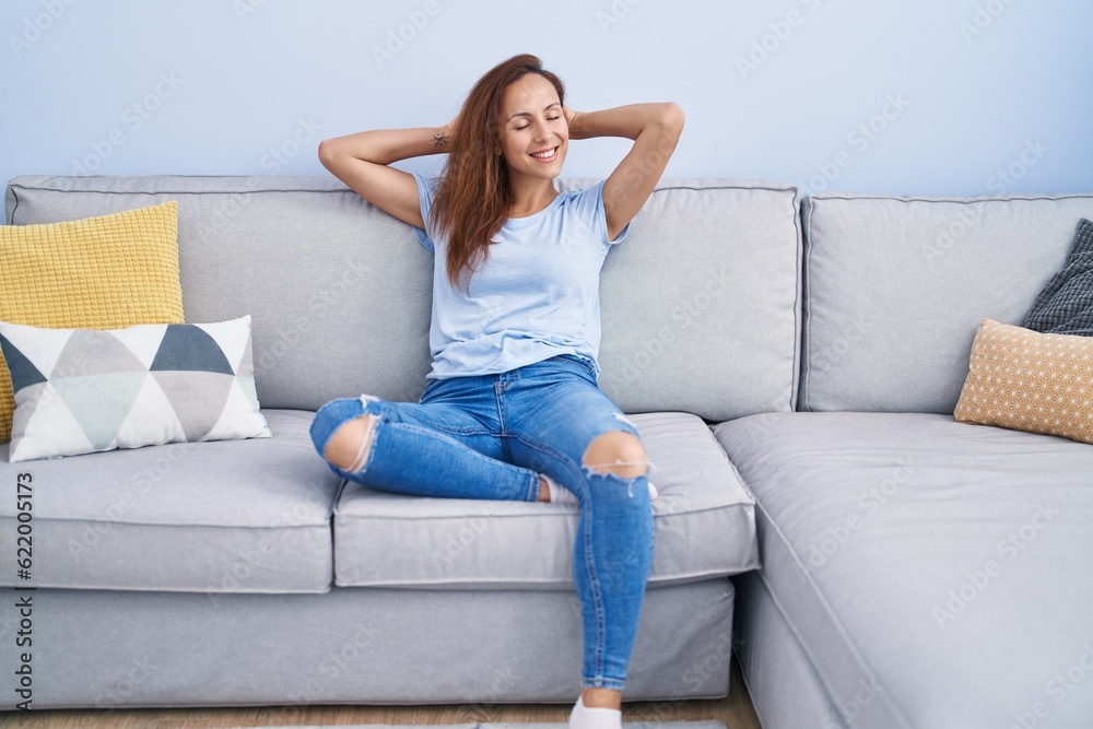 Young woman relaxed with hands on head sitting on sofa at home Young woman relaxed with hands on head sitting on sofa at home