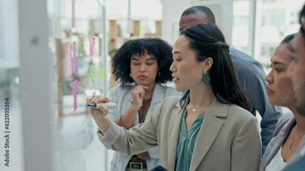 Asian woman, coach and writing on glass board in team brainstorming for schedule planning at office. Female person coaching or training staff on sticky note for strategy or project plan at workplace