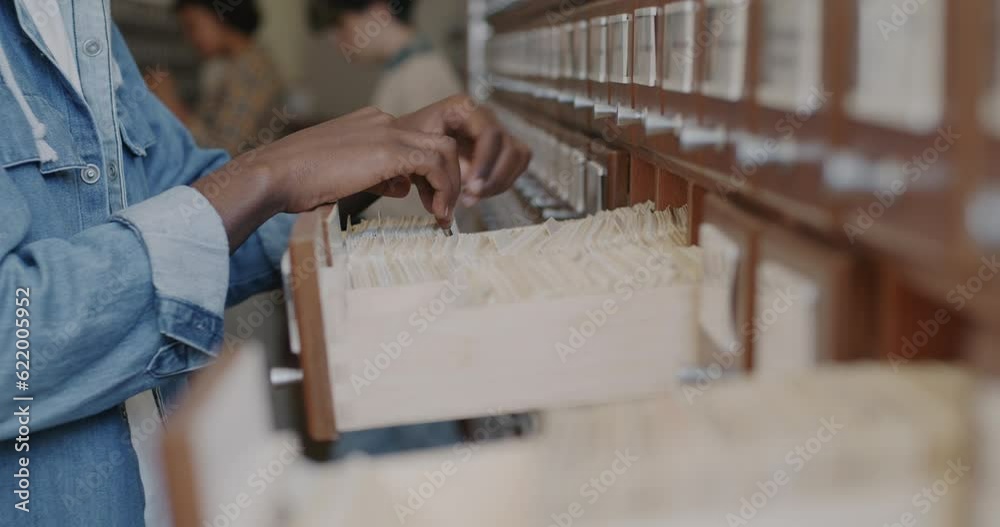 Close-up slow motion of male hands searching books in library archives while African American man preparing academic research. Reading and literacy concept.
