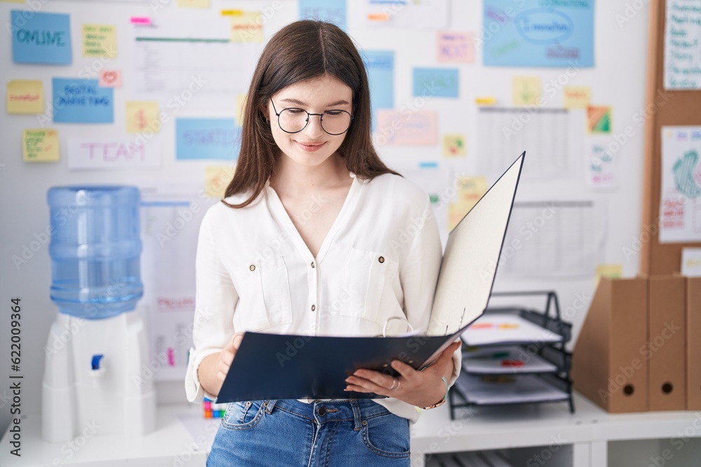 Young caucasian woman business worker smiling confident reading document at office Young caucasian woman business worker smiling confident reading document at office