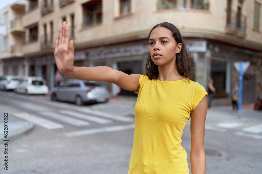 Fototapeta premium Young african american woman doing stop gesture with hand at street