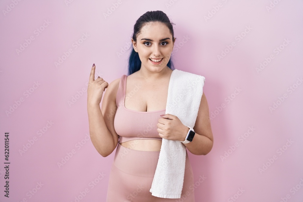 Young modern girl with blue hair wearing sportswear over pink background pointing finger up with successful idea. exited and happy. number one. Young modern girl with blue hair wearing sportswear over pink background pointing finger up with successful idea. exited and happy. number one.