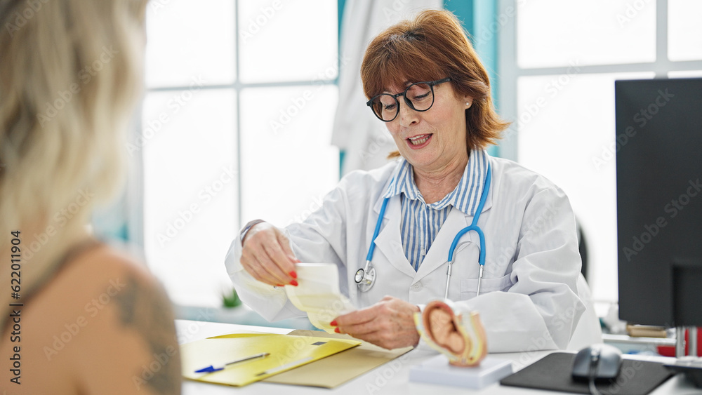 Obraz premium Middle age woman doctor and patient showing ultrasound baby at clinic