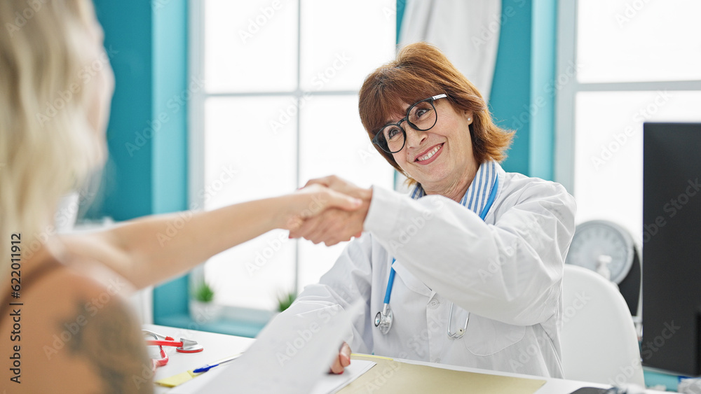 Middle age woman doctor and patient shake hands having medical consultation at clinic Middle age woman doctor and patient shake hands having medical consultation at clinic