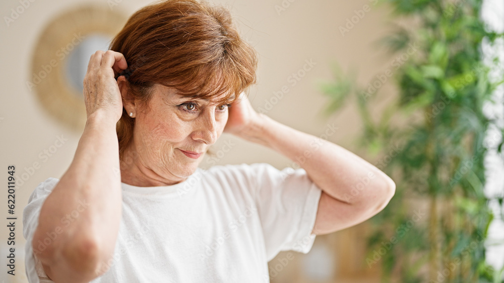 Middle age woman combing hair at bedroom