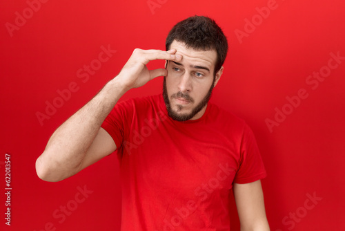 Young hispanic man wearing casual red t shirt worried and stressed about a problem with hand on forehead, nervous and anxious for crisis