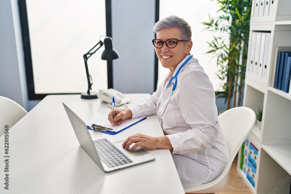Middle age woman wearing doctor uniform working at clinic Middle age woman wearing doctor uniform working at clinic
