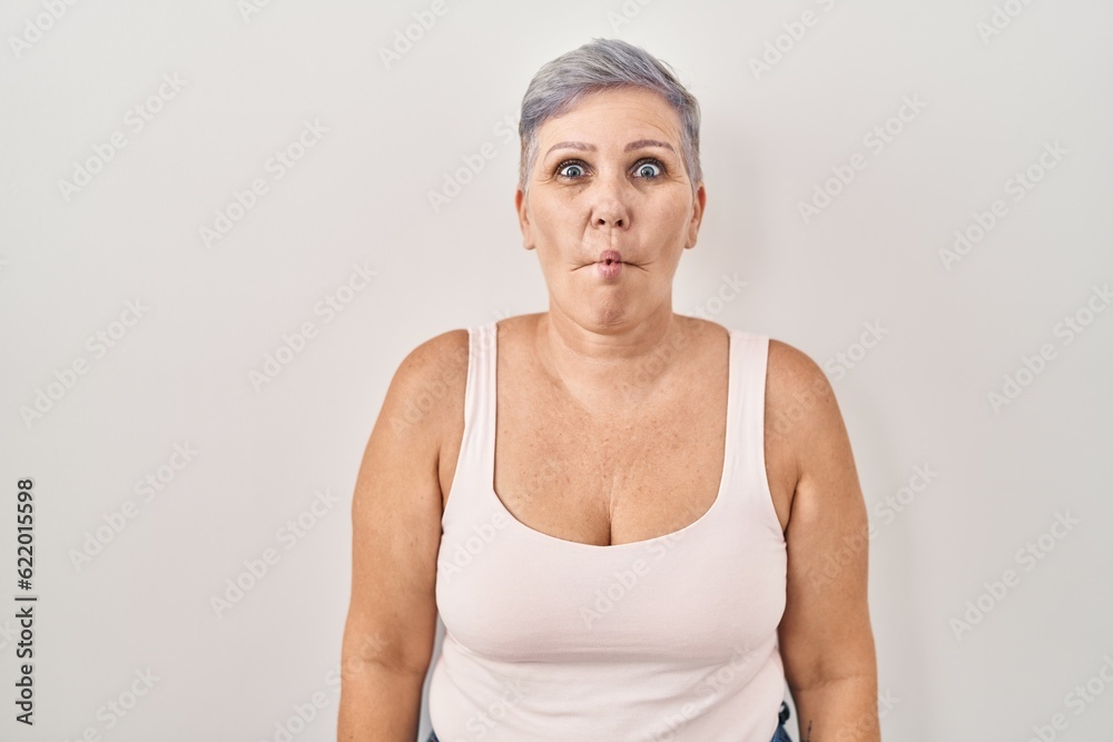 Middle age caucasian woman standing over white background making fish face with lips, crazy and comical gesture. funny expression. Middle age caucasian woman standing over white background making fish face with lips, crazy and comical gesture. funny expression.
