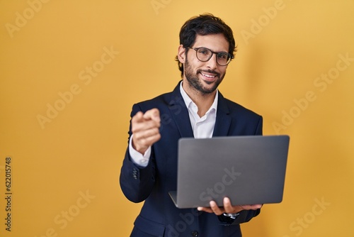 Handsome latin man working using computer laptop pointing fingers to camera with happy and funny face. good energy and vibes.