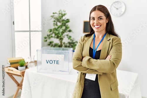 Young beautiful hispanic woman electoral table president standing with arms crossed gesture at electoral college